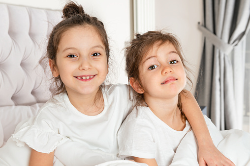 Unrecognizable two cute little girls smiling having fun at pajamas party.