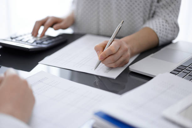 istock Woman accountant using a calculator and laptop computer while counting taxes for a client. Business audit concepts 1492396366