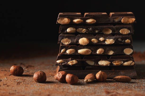 istock Dark and milk chocolate with nuts on a dark background sprinkled with cocoa powder. 1492399573