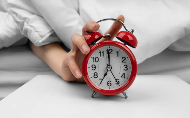 istock Woman's hand turning off red alarm clock on night table 1492400820