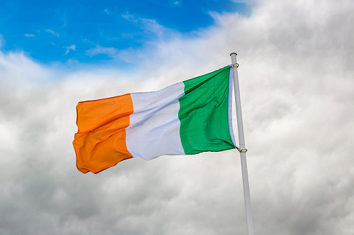 Irish flag waving in the wind against cloudy sky
