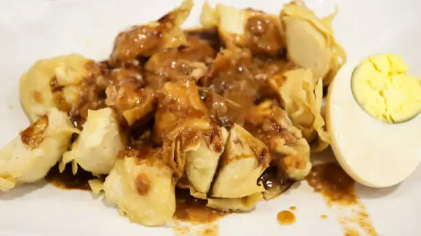 Photo of Close up of Batagor siomay Bandung popular street food from Bandung, Indonesia, consist of tofu, fish cake, boiled potato and egg, with peanut sauce.