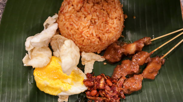 istock Fried rice, prawn crackers, sunny side up egg, fried anchovies, peanuts and chicken satay served on top of banana leaves. 1492405719