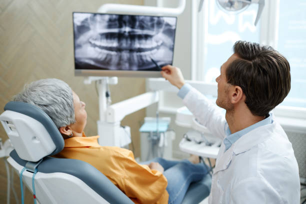 rückansicht eines männlichen zahnarztes, der auf das röntgenbild des zahns auf dem bildschirm zeigt - zahnarztpraxis stock-fotos und bilder