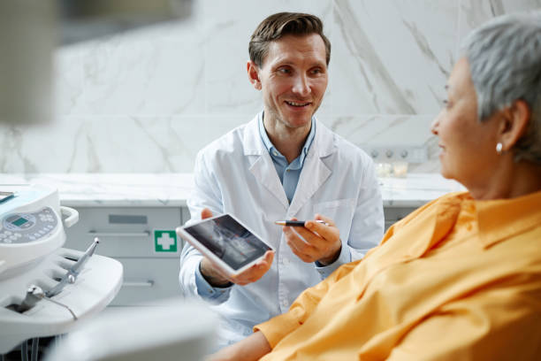 歯のx線画像を持つデジタルタブレットを持つ笑顔の男性歯科医 - happiness women senior adult two people ストックフォトと画像
