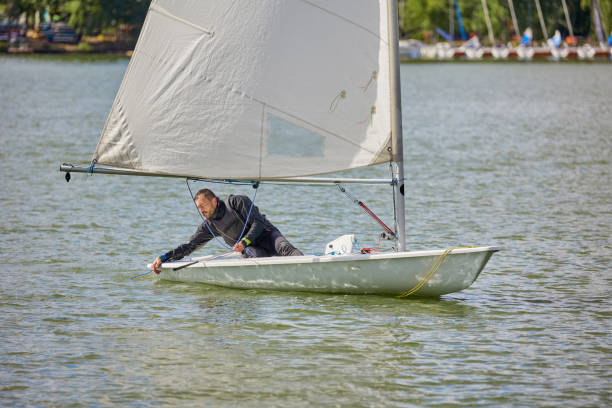 man on laser boat with sail on water man practice sailing on laser boat in the lake sailing dinghy stock pictures, royalty-free photos & images