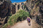 Happy family hiking towards the magnificent Puente Nuevo in Ronda, Andalusia, Spain.