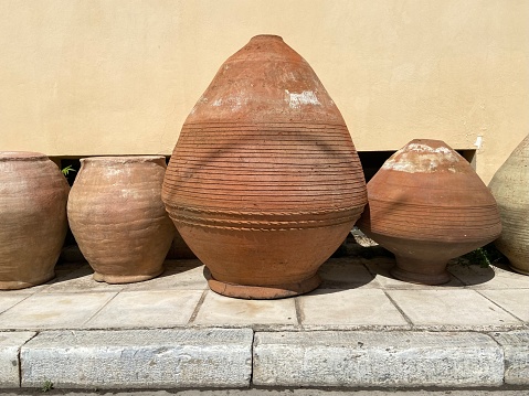 A row of pottery in different shapes and sizes lined up outdoors against the wall in the Keramikos neighborhood of Athens, Greece