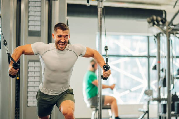 istock A sportsman is shouting in a gym while lifting heavy weights on a cable machine in a gym. 1492412231