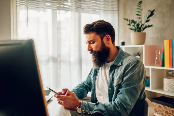 istock Side view of a digital marketing worker sitting at the home office and adding content on social media on his phone. 1492414042