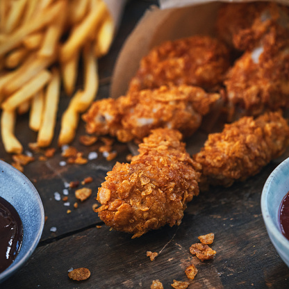 Crispy fried chicken drumsticks accompanied with golden-brown French fries. The chicken drumsticks are perfectly cooked to a rich golden color, showcasing a tantalizingly crunchy exterior.