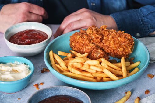 Crispy fried chicken drumsticks accompanied with golden-brown French fries. The chicken drumsticks are perfectly cooked to a rich golden color, showcasing a tantalizingly crunchy exterior.