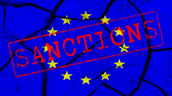 Red inscription SANCTIONS on the background of the flag of the European Union and cracks
