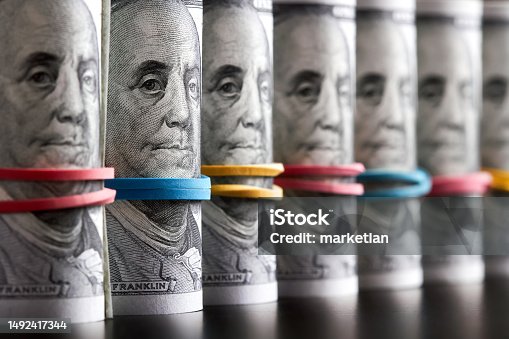 istock A row of rolled hundred dollar bills with rubber bands on dark background 1492417344