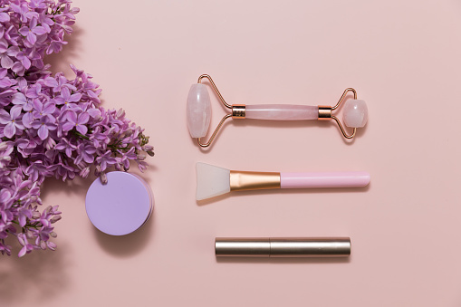 Beauty products on a pink background with lilac