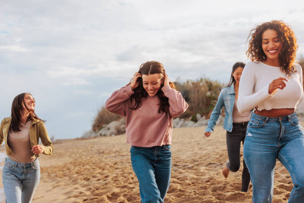 istock Four young women running happily on beach. 1492420579