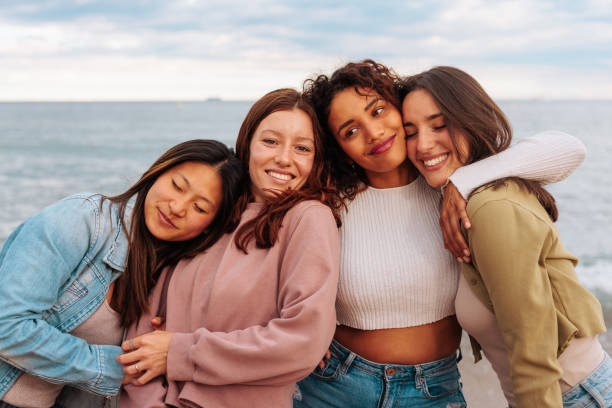 istock Four young multiracial women in 20s hugging while standing on beach. 1492420587