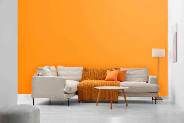 istock Stylish sofa and coffee table in room with orange walls. Interior design 1492422478