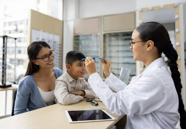 istock Optician putting glasses on a boy at the ophthalmologist store 1492423067