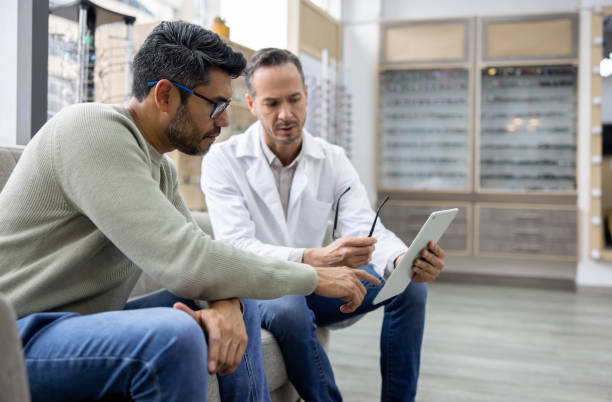 Optician performing an eye exam on a man while wearing glasses
