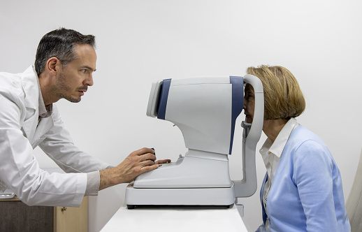 Latin American optometrist performing an eye exam on a patient using an eye scanner