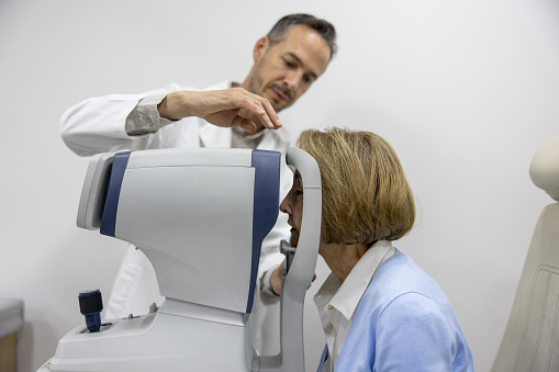 Closeup of a technician preparing a early 40's female patient for a head MRI scan. The technician is putting plastic fixation over patient's head after which the procedure starts.