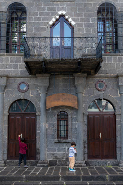 image of brothers playing in front of historic stone house.Historic house made of wooden door and volcanic stone. brothers spending time together in street. Shot with a full-frame camera in daylight.