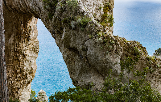 Beautiful view of the natural arch in the rock against the backdrop of the Tiranian sea on the island of capri italy,side view close-up.