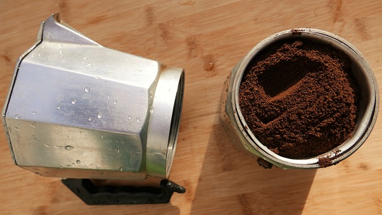 An open coffee pot on the table. Espresso coffee. Preparing coffee in a Moka Pot. Coffee powder on the table. Ground coffee beans, top angle. Italian coffee maker, top angle. Coffee day. Preparing a cup of coffee.