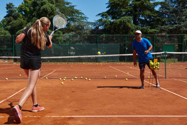 uma tenista profissional e seu treinador treinando em um dia ensolarado na quadra de tênis. treinamento e preparação de um tenista profissional - tennis coach serving playing - fotografias e filmes do acervo