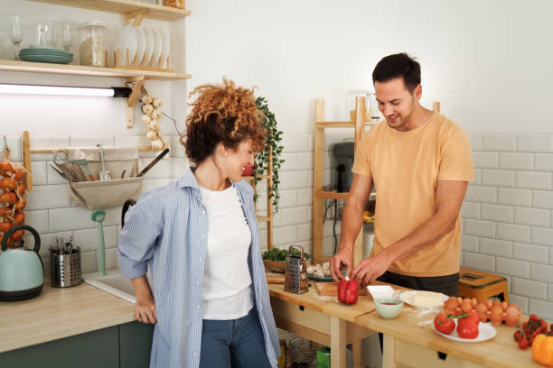istock Young smiling couple making pizza in a domestic kitchen together 1492441883