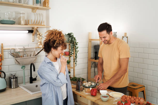 istock Young smiling couple making pizza in a domestic kitchen together 1492441921