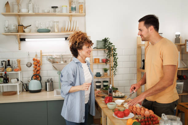 istock Young smiling couple making pizza in a domestic kitchen together 1492441922