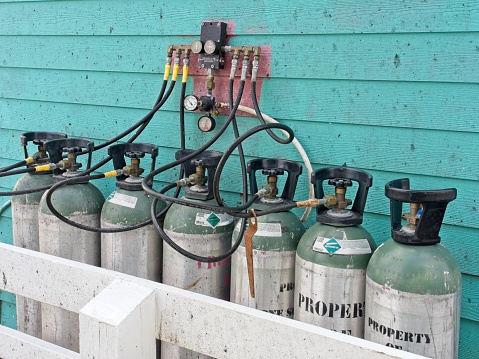 Carbon dioxide cylinders lined up along a coastline beachside restaurant on Galveston island Texas. Aqua wall contrasts with aluminum cylinders.