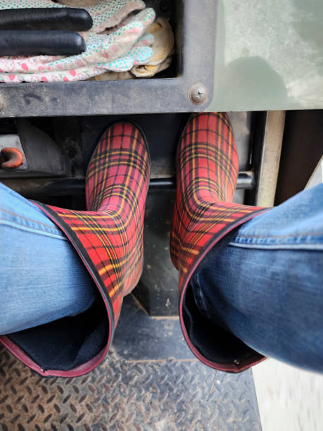 woman sitting in atv wearing plaid rubber boots. - fashion women denim farm imagens e fotografias de stock