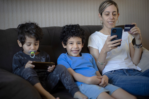 Mother and children on the sofa using the cell phone