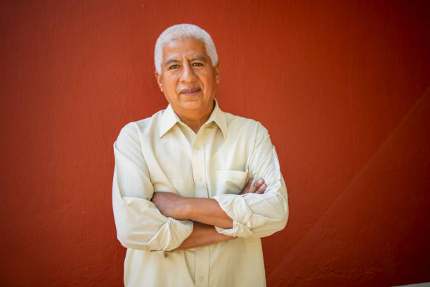 портрет латинского пожилого человека, смотрящего в камеру на красном фоне - mexico only men senior men mature men стоковые фото и изображения