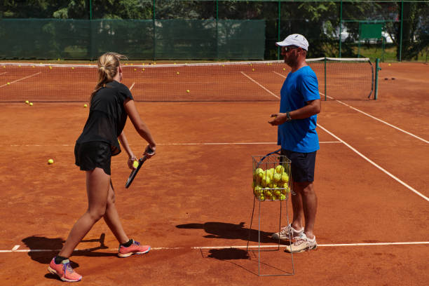 uma tenista profissional e seu treinador treinando em um dia ensolarado na quadra de tênis. treinamento e preparação de um tenista profissional - tennis coach serving playing - fotografias e filmes do acervo