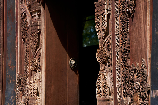 Artistic Woodcarving: Intricate Door Panel Design in a Thai Temple.