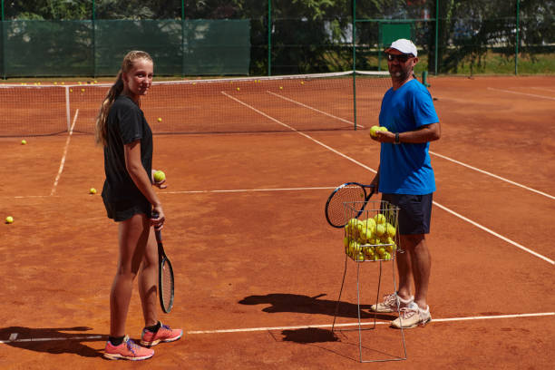 uma tenista profissional e seu treinador treinando em um dia ensolarado na quadra de tênis. treinamento e preparação de um tenista profissional - tennis coach serving playing - fotografias e filmes do acervo