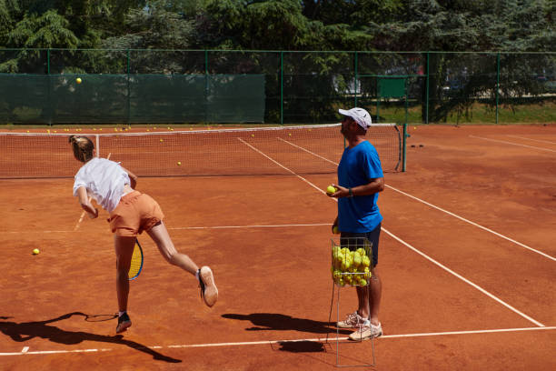 uma tenista profissional e seu treinador treinando em um dia ensolarado na quadra de tênis. treinamento e preparação de um tenista profissional - tennis coach serving playing - fotografias e filmes do acervo