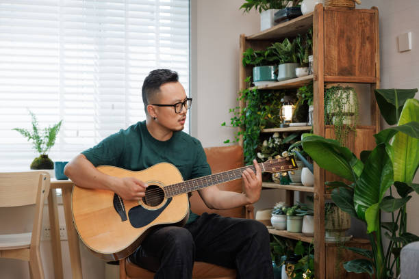 istock Middle aged man playing guitar at home 1492469871