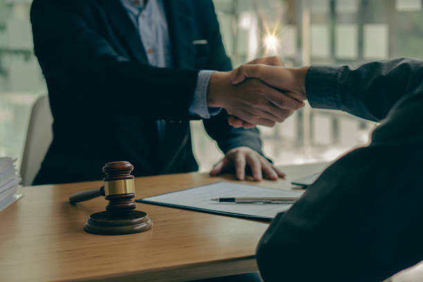 lawyers shaking hands Businessman shaking hands to seal a deal with his partner lawyers or attorneys discussing a contract agreement.Legal law, advice, and justice concept stock photo