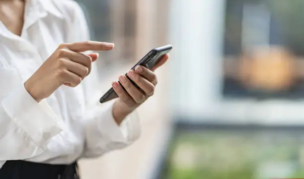 Photo of woman's hand with mobile phone Young woman tapping finger on blank screen of smartphone to click line and play social media online shopping job.
