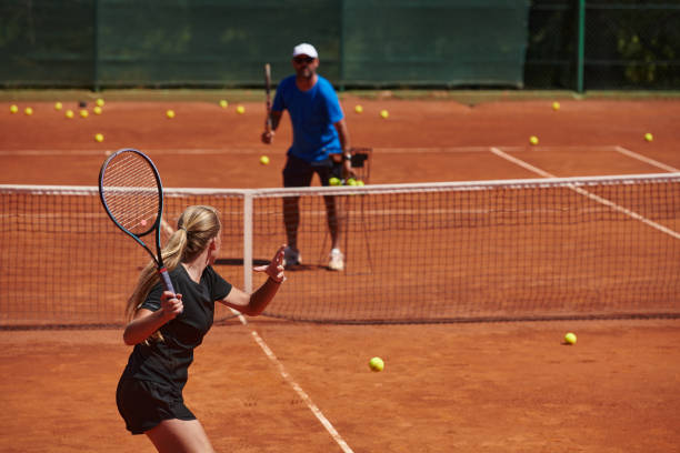 uma tenista profissional e seu treinador treinando em um dia ensolarado na quadra de tênis. treinamento e preparação de um tenista profissional - tennis coach serving playing - fotografias e filmes do acervo