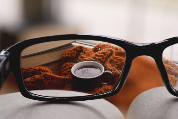 Looking through corrective eyeglasses lenses at cup of tea wrapped in warm scarf