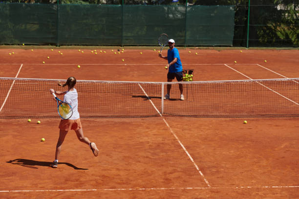 uma tenista profissional e seu treinador treinando em um dia ensolarado na quadra de tênis. treinamento e preparação de um tenista profissional - tennis coach serving playing - fotografias e filmes do acervo