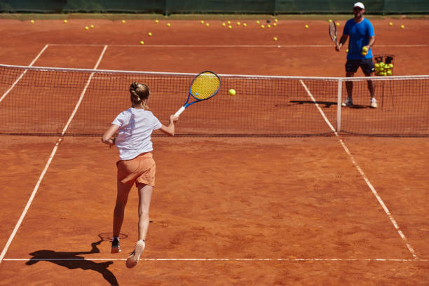 uma tenista profissional e seu treinador treinando em um dia ensolarado na quadra de tênis. treinamento e preparação de um tenista profissional - tennis coach serving playing - fotografias e filmes do acervo