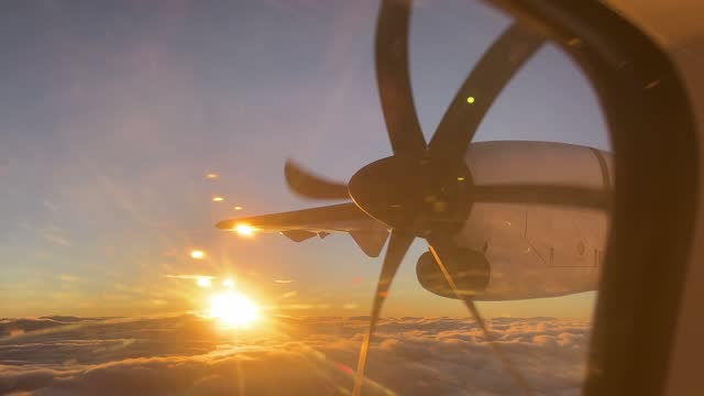 View from the window of the aircraft on a rotating propeller against the backdrop of sunset