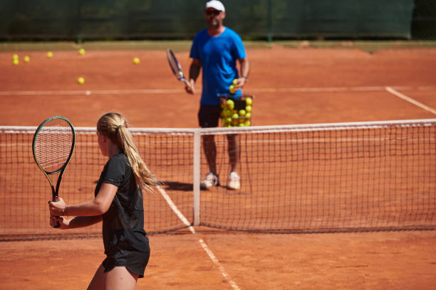 uma tenista profissional e seu treinador treinando em um dia ensolarado na quadra de tênis. treinamento e preparação de um tenista profissional - tennis coach serving playing - fotografias e filmes do acervo